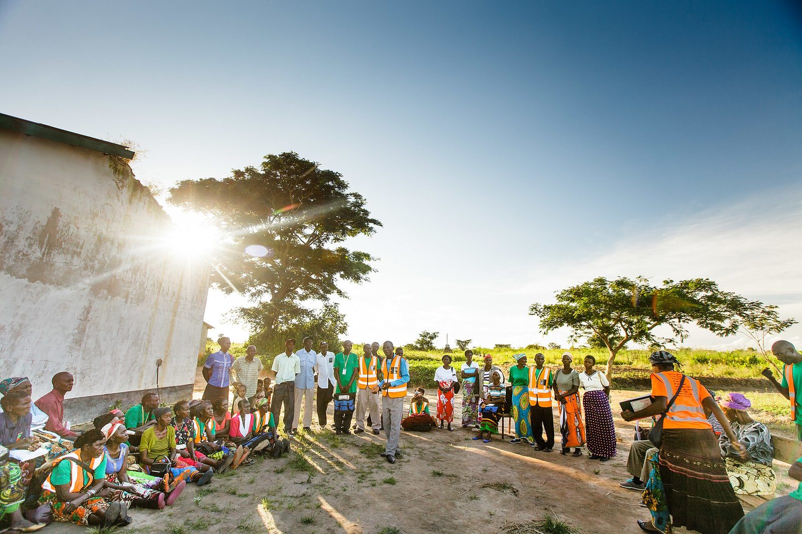 Community members gathered outdoors for a village project planning meeting in Zambia