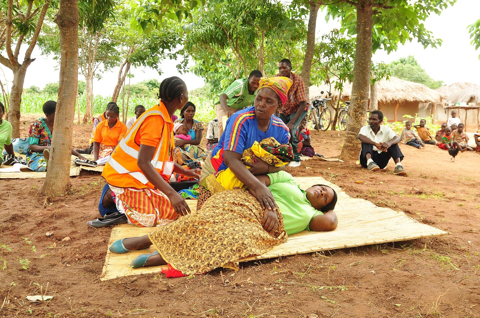 Health outreach volunteers supporting a patient during a rural community visit in Zambia